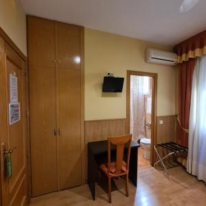 Habitación con escritorio, silla y TV. en Hostal Oporto, en Madrid
