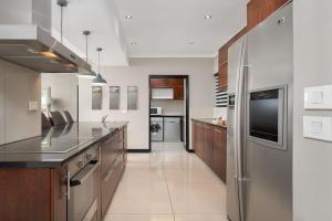 duża kuchnia z urządzeniami ze stali nierdzewnej i drewnianymi szafkami w obiekcie Icon Luxury Apartments w Kapsztadzie