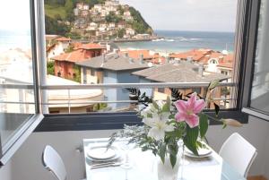 a vase of flowers on a table with a view of the ocean at Go Donosti Chillida in San Sebastián