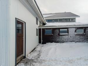 a white building with a door in the snow at Grásteinn Guesthouse in Þórshöfn