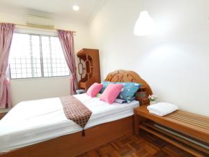 una camera da letto con un letto con cuscini rosa e blu di NanSang One Homestay 8pax 4Rooms a Sibu