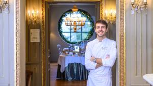 un hombre con un traje de chef parado frente a una mesa en Hôtel Restaurant Spa Le Sauvage en Besanzón