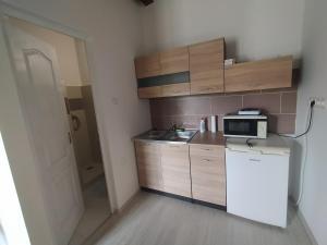 a small kitchen with a microwave and a refrigerator at Heni Vend&eacute;gh&aacute;za in Vadna