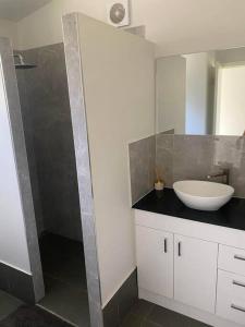 a bathroom with a white sink and a shower at Rural Self Contained 3 bedroom Cottage on acreage, in Landsborough