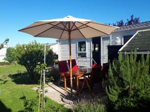 a table with an umbrella in front of a house at ZP 237 - Camping de Zandput in Vrouwenpolder