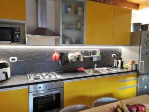 a kitchen with yellow cabinets and a stove and a sink at POETI&MISùLTIN. POESIA E VACANZA SUL LAGO in Menaggio