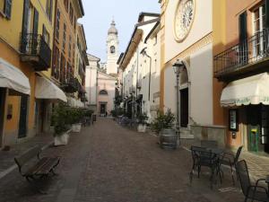 an empty street with tables and chairs and a clock tower at POETI&MISùLTIN. POESIA E VACANZA SUL LAGO in Menaggio +10 photos