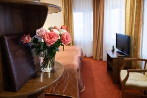 un vase de roses sur une table dans une chambre d'hôtel dans l'établissement 40th Meridian Arbat Hotel, à Kolomna