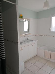 a white bathroom with a tub and a sink at maison d'hôtes in Saint-Julien-lʼArs