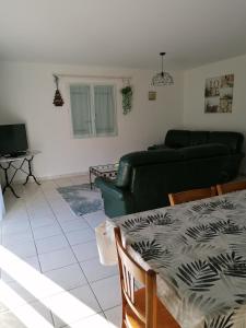 ein Wohnzimmer mit einem grünen Sofa und einem Tisch in der Unterkunft maison d'hôtes in Saint-Julien-lʼArs