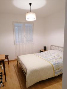a white bedroom with a bed and a table at maison d'hôtes in Saint-Julien-lʼArs