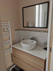 W łazience znajduje się biała umywalka i lustro. w obiekcie Maison au cœur de migennes w mieście Migennes