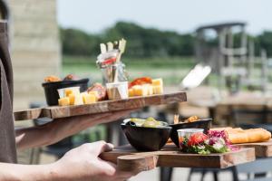 eine Person, die ein Tablett mit Essen auf einem Tisch hält in der Unterkunft Vakantiewoning Boerderij De Gerrithoeve in Oisterwijk