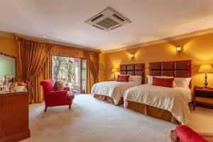 a large bedroom with two beds and a red chair at Lejwe La Metsi Private Reserve in Bela-Bela