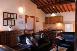 a living room with black leather chairs and a kitchen at Villa Cenerentola in Trequanda