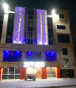 une moto garée devant un immeuble avec des lumières violettes dans l'établissement Golden Heaven Hotel, à Kolkata