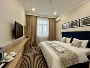 ein Schlafzimmer mit einem großen Bett und einem Flachbild-TV in der Unterkunft Bristol Hotel Tashkent in Taschkent