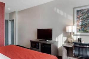 a hotel room with a bed and a flat screen tv at Comfort Inn & Suites near Stadium in Bronx