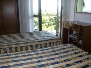 um quarto com uma cama, uma secretária e uma varanda em Hotel Santorotto em Sinalunga