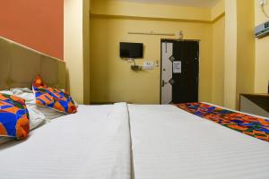 a bedroom with two beds and a door with a television at FabHotel DP International in Patna