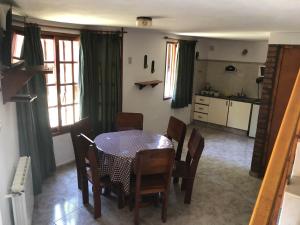 cocina y comedor con mesa y sillas en Cabañas Los Aromos en Embalse
