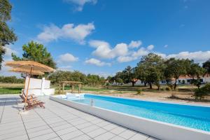 a swimming pool with an umbrella and a table and chairs at Herdade do Vale da Abelheira by MyStay in Grândola