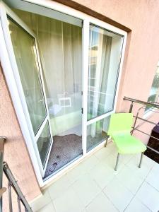 una puerta corredera de cristal con una silla verde en el balcón en Lotos Лотос, en Adler