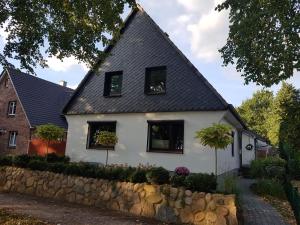 une maison blanche avec des fenêtres noires et un mur en pierre dans l'établissement Ferienwohnung-Haus Holly, à Uetersen