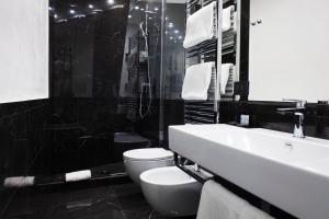 Baño en blanco y negro con aseo y lavamanos en LHP Suite Napoli Parco Margherita, en Nápoles