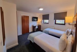 a hotel room with two beds and a desk at Premier Lodge in Falkirk