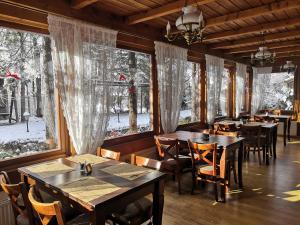 a dining room with tables and chairs and windows at Czarny Potok Wellness & Spa Zakopane Centrum in Zakopane