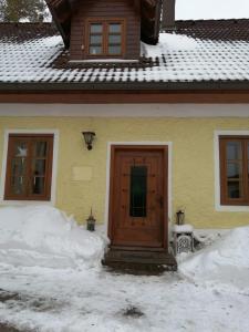 a house with a wooden door in the snow at Apartment Nazbauerhof in Rohr im Gebirge