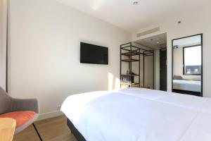 a bedroom with a large white bed and a mirror at Fletcher Hotel Rotterdam-Airport in Rotterdam