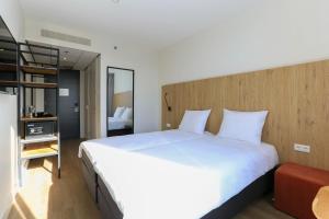 Fletcher Hotel Rotterdam-Airport في روتردام: غرفة نوم مع سرير أبيض كبير في غرفة