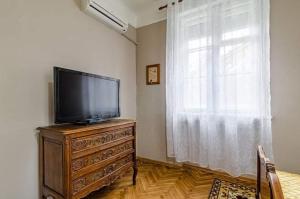a living room with a television on a dresser with a window at Апартамент Жасмин in Varna City