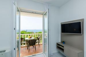 a room with a balcony with a table and a television at Villa Panorama Dubrovnik in Mlini