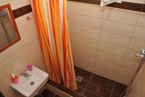 a bathroom with an orange shower curtain next to a sink at GUESTHOUSE BLOUTSOS ROOMS in Kastraki