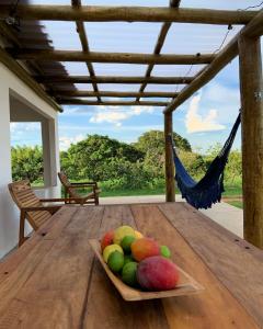 a bowl of fruit on a wooden table with a hammock at Lostpoint Home in Monte Alto