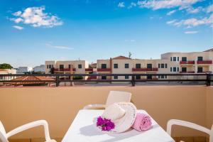 a hat and flowers on a table on a balcony at Kambos Village in Agia Marina Nea Kydonias