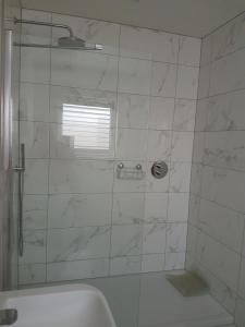 a bathroom with a shower with a tub and a sink at Petite Anchorage in Christchurch