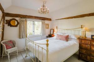 a bedroom with a bed and a window and a chandelier at Water Cottage, a perfect ancient House in Suffolks prettiest tiny village in Kersey