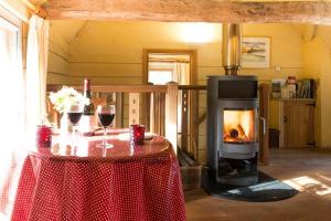 a living room with a fireplace and a table with wine glasses at Mill Cottage set beside a Mill pond in a 70 acre Nature Reserve Bliss in Assington