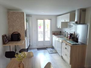 a kitchen with white cabinets and a refrigerator and a table at Agréable logis au calme avec jardin entre PARIS et EURODISNEY in Rosny-sous-Bois