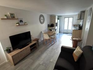 a living room with a flat screen tv and a table at Agréable logis au calme avec jardin entre PARIS et EURODISNEY in Rosny-sous-Bois