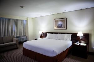 a hotel room with a large bed and a chair at Eurobuilding Express Barinas in Barinas