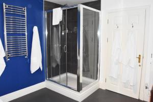 a bathroom with a glass shower with blue walls at Patricks Boathouse in Swansea