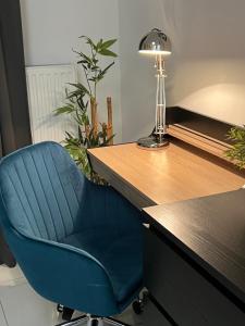 a blue chair sitting next to a desk with a lamp at GREEN 25 - Angel River in Wrocław
