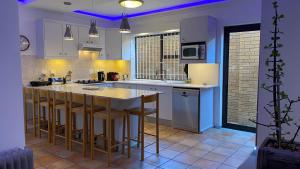 a kitchen with white cabinets and a island with bar stools at Charming Sea Side Sun Apartment in Hermanus