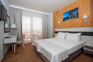 アナパにあるSunmarinn Resort All Inclusiveの大きなベッドとデスクが備わるホテルルームです。