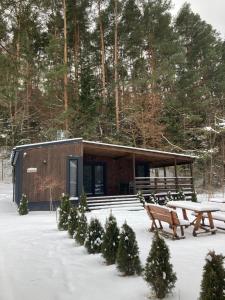 uma cabana na neve com uma mesa e bancos em Sarzynówka pod Sosną em Krasnobród